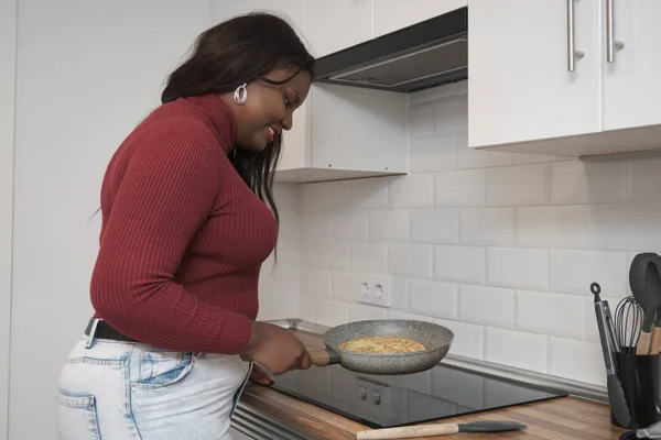Young african american woman smiling and preparing Spanish potato omelette. — Stock Photo, Image