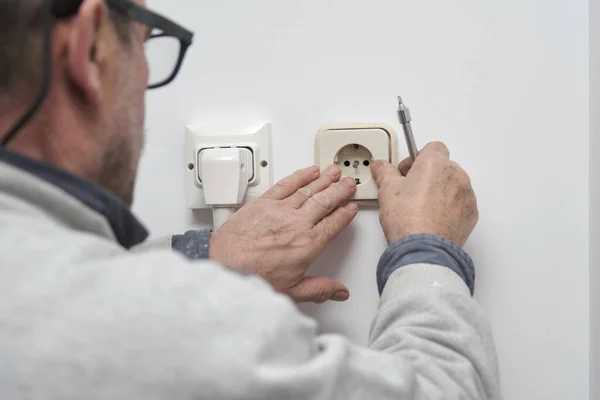 Electricista senior instalando un enchufe eléctrico en una casa nueva. —  Fotos de Stock