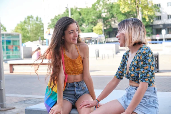 Jong lesbisch paar flirten en glimlachen zitten op een bank buiten. — Stockfoto
