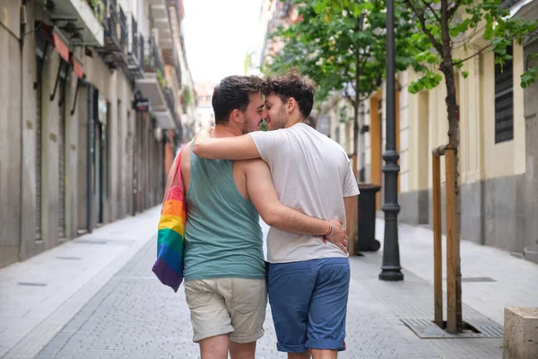 Gay coppia circa per bacio mentre a piedi e abbracciare in il strada indietro. — Foto Stock