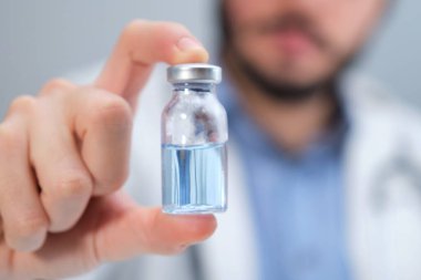 Mavi bir şişe tutan tanınmayan bir doktor..