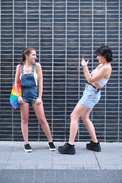 Um casal lésbico tirando fotos um para o outro com um smartphone. — Fotografia de Stock