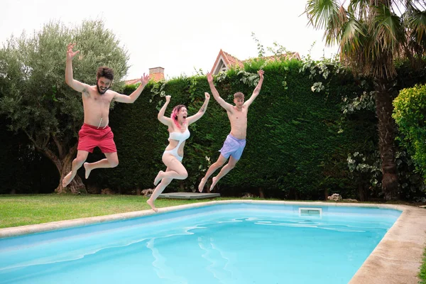 Grupp om tre vänner hoppar i poolen. — Stockfoto