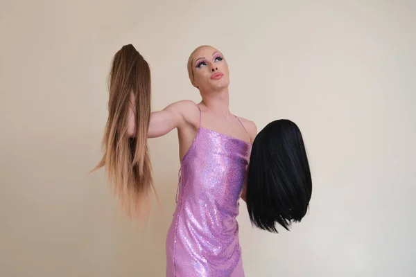 Drag queen πρόσωπο φορώντας παγιέτες ροζ φόρεμα επιλέγοντας μια περούκα. — Φωτογραφία Αρχείου