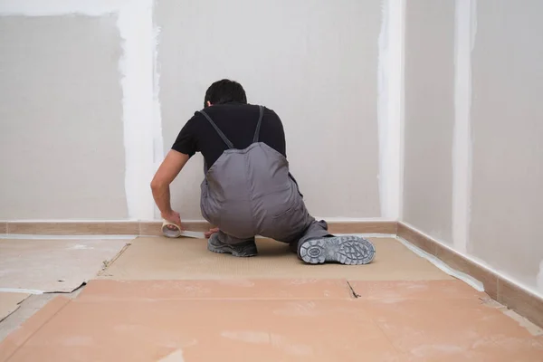 Pintor usando cinta y cartón para cubrir el suelo antes de pintar la habitación. —  Fotos de Stock