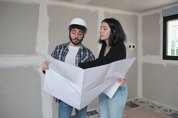 Arquitecto muestra apartamento en planos de construcción a mujer joven interesada. — Foto de Stock