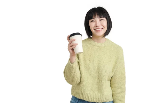 Νεαρή Ασιάτισσα χαμογελαστή με μια κούπα καφέ, φορώντας χειμωνιάτικο πουλόβερ, απομονωμένη. — Φωτογραφία Αρχείου