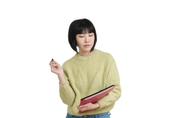Νεαρή Ασιάτισσα μαθήτρια γράφει σε μια εφημερίδα, φοράει πράσινη μπλούζα, απομονωμένη. — Φωτογραφία Αρχείου