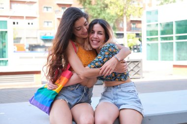 Genç lezbiyen çift dışarıda sarılıp gülümsüyor..