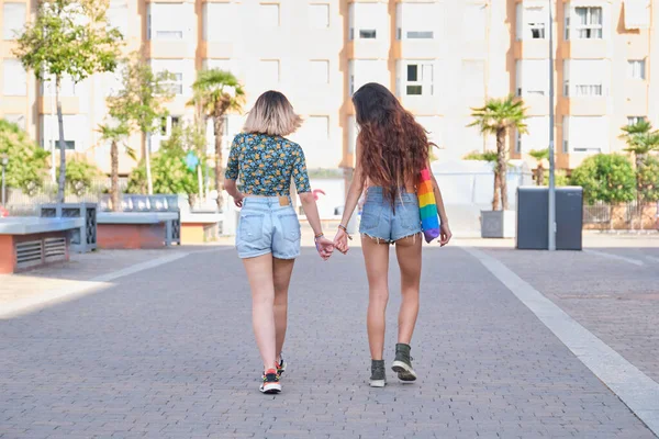 Jong lesbisch paar vasthouden handen en lopen achteruit. — Stockfoto