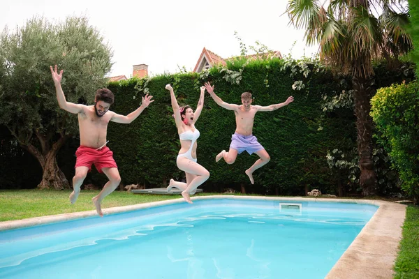 Grupp om tre vänner hoppar i poolen. — Stockfoto