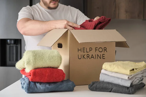 Volontariato riempimento scatola di donazione con vestiti per aiutare i rifugiati ucraini. — Foto Stock