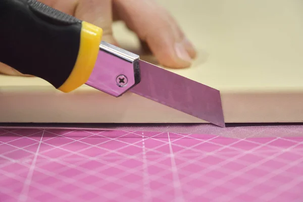 Man cutting frosted window vinyl with a cutter.