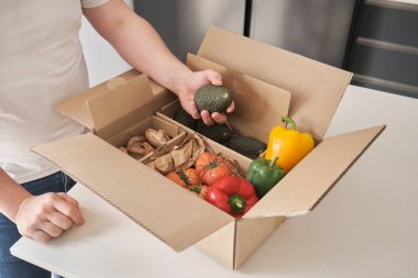 Meyve ve sebze karton bir kutu avokado tutan tanınmamış bir adam..