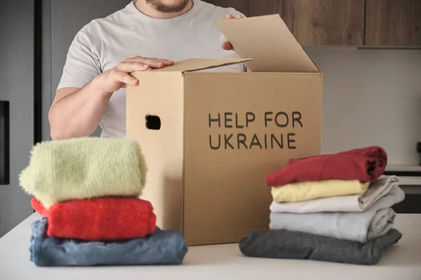 Volontariato riempimento scatola di donazione con vestiti per aiutare i rifugiati ucraini. — Foto Stock