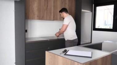 Genç İspanyol adam mutfağa tezgah koymadan önce mezura kullanıyor..