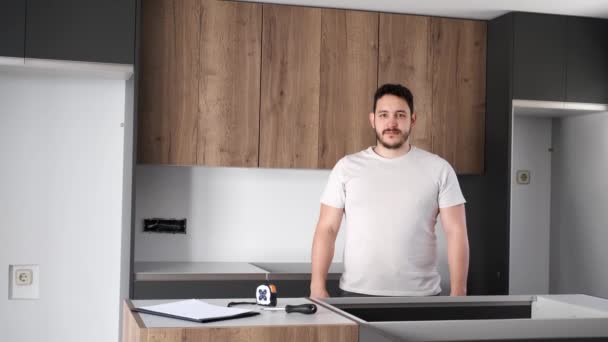 Mladý latinský muž úsměv a zkřížit ruce po instalaci kuchyňského nábytku. — Stock video