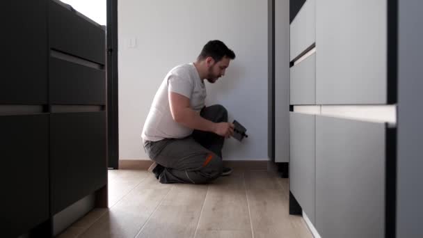 Joven latino instalando zócalo en una nueva cocina moderna. — Vídeo de stock