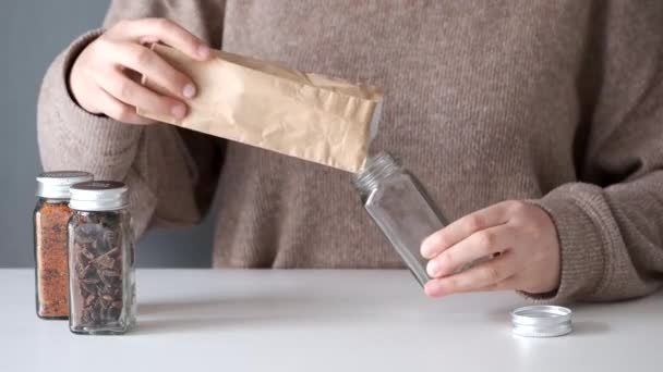 Kırpılmış kadın, baharat kavanozunu kese kağıdından kuru arnavut biberiyle dolduruyor.. — Stok video
