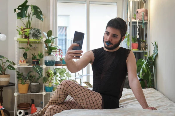 Joven hombre usando maquillaje y medias de rejilla tomando una selfie con el teléfono. — Foto de Stock