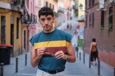 Sokakta güneş gözlükleriyle poz veren uzun takma tırnaklı beyaz bir genç..