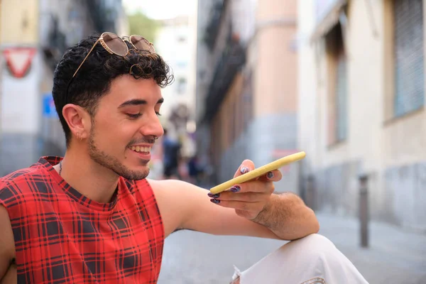 Uzun takma tırnaklı beyaz bir adam yerde oturan bir sesi kaydediyor..