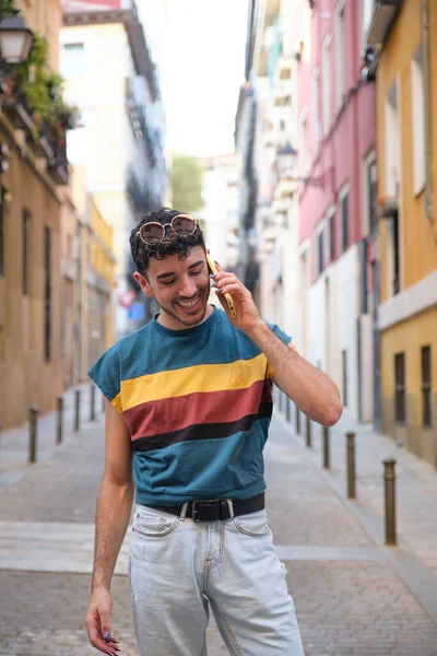 Uzun takma tırnaklı, gülümseyen ve telefonla konuşan beyaz bir genç..