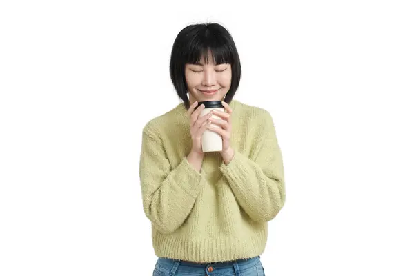 年轻的亚洲女人笑着闻着咖啡杯 穿着冬季绿色毛衣 与白色背景隔离 — 图库照片