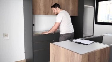Genç Arjantinli adam mutfağa tezgah yerleştirmeden önce mezura kullanıyor..