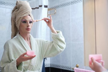 Duştan sonra yanaklarına allık süren travesti..