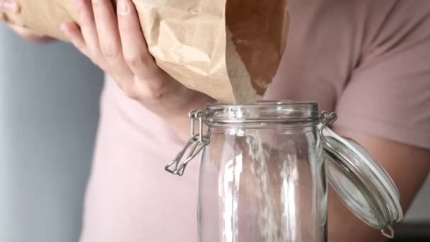 Unrecognizable man filling up a jar with whole wheat flour from a paper bag. — Stockvideo