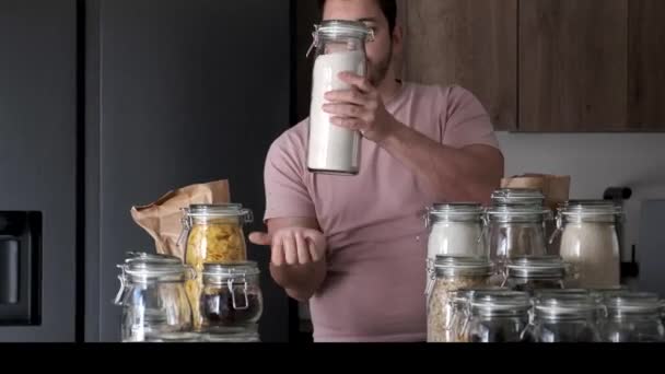 Young latin man filling up a jar with whole wheat flour from a paper bag. — Stockvideo