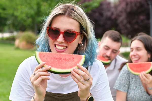 Elinde bir karpuz parçasıyla gülümseyen mutlu bir genç kadın..