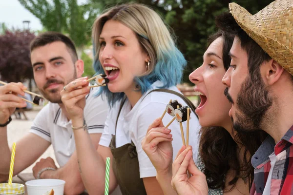 一群快乐的朋友在一个野餐的公园里笑着吃寿司. — 图库照片