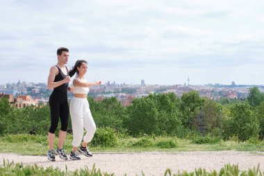 Genç ve sportif bir çift dışarıda koşuşturup etrafı kolaçan ediyor. İki koşucu arkadaş.