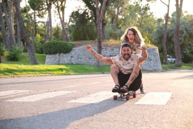 Genç, havalı dövmeli çift kaykay yaparken eğleniyor..