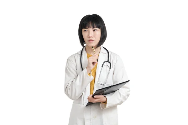 Молода азіатська жінка-лікар мислення з ручкою і текою, ізольовані . — стокове фото