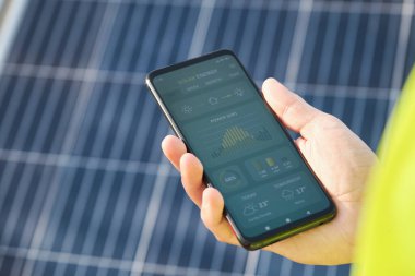 Hand showing a solar power generation smartphone app.
