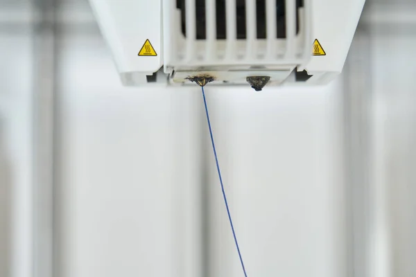 stock image Blue plastic filament extruding through 3D printer nozzle.