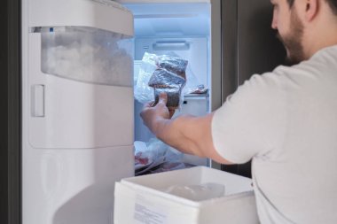 Genç Latin adam, haftalık balık teslimatını dondurucuya koydu..