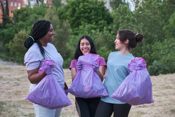 Mujeres multirraciales hablando, riendo y sosteniendo bolsas de basura de trotar. — Foto de Stock