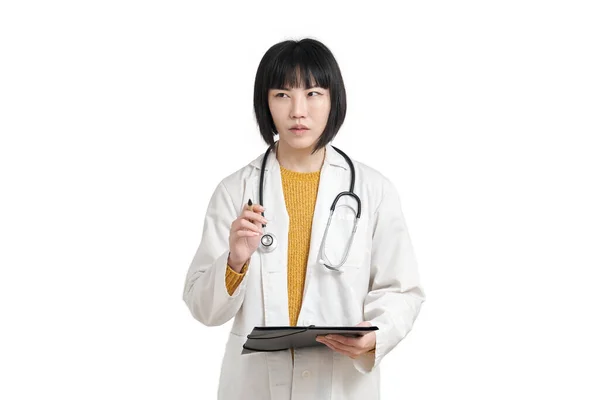 Młoda azjatycka lekarz myśli z piórem i folderu, izolowane. — Zdjęcie stockowe