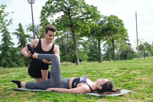 Personal trainer aiutare la giovane donna in un parco con esercizi di stretching. — Foto Stock