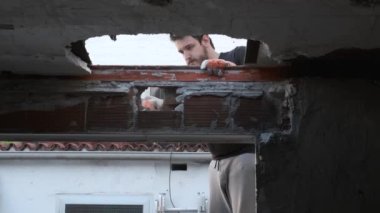 Genç adam tokmak kullanarak evin tavanını aşağı çekiyor..