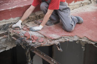 Tanınmayan bir adam tokmak kullanarak bir evin çatısını yıkıyor..
