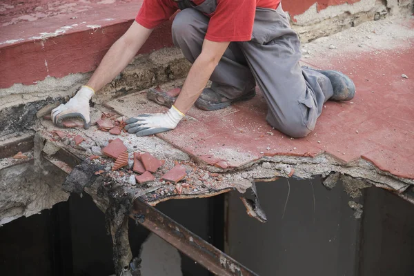 Tanınmayan bir adam tokmak kullanarak bir evin çatısını yıkıyor..