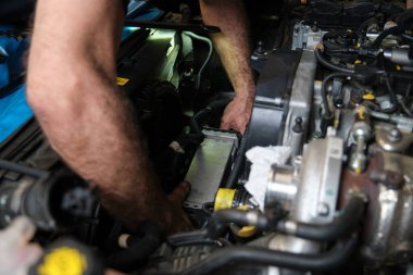 Araba tamircisinin elleri bir araba motorunun soğutucusunu değiştiriyor. Mekanik atölyesi.