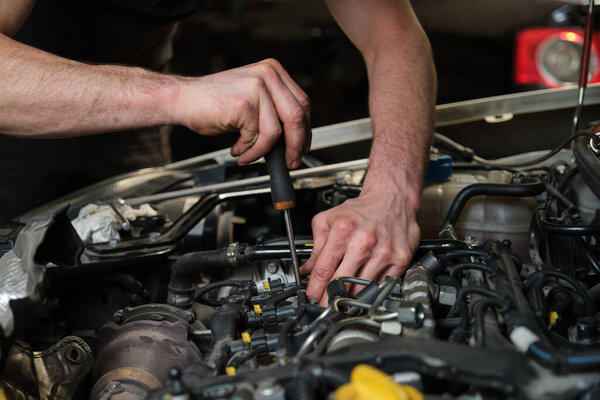 Крупный план механической руки автомобиля, удаляющей топливные форсунки в машинном отделении, проверяющей пыль и испытательное давление в процессе технического обслуживания.