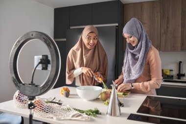 Modern mutfakta salatanın nasıl hazırlanacağını anlatan iki müslüman yemek vlogcusu..