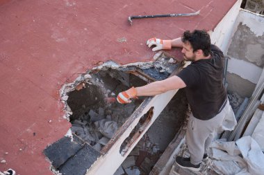 Genç bir adam tokmakla evin tavanını yıkıyor..